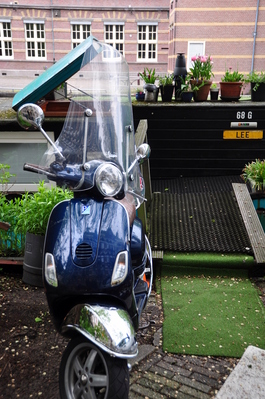 Scooter parked outside a houseboat with flowers