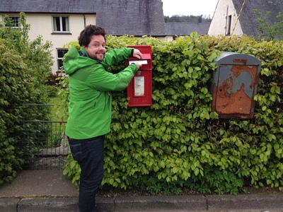 Mike mailing a postcard into a hedge